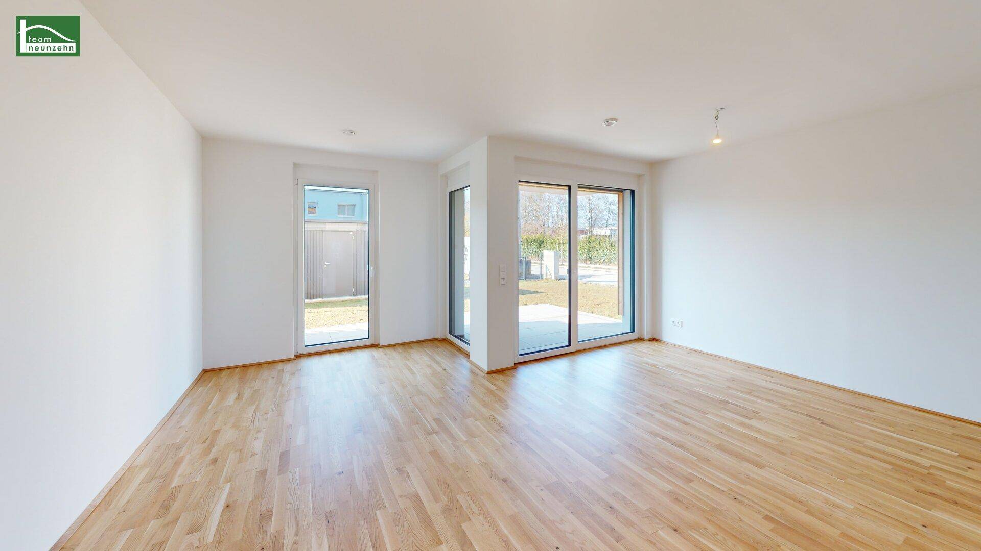 Heller, leerer Wohnbereich mit großen Fenstern und Zugang zum Garten, ideal für individuelle Gestaltung.