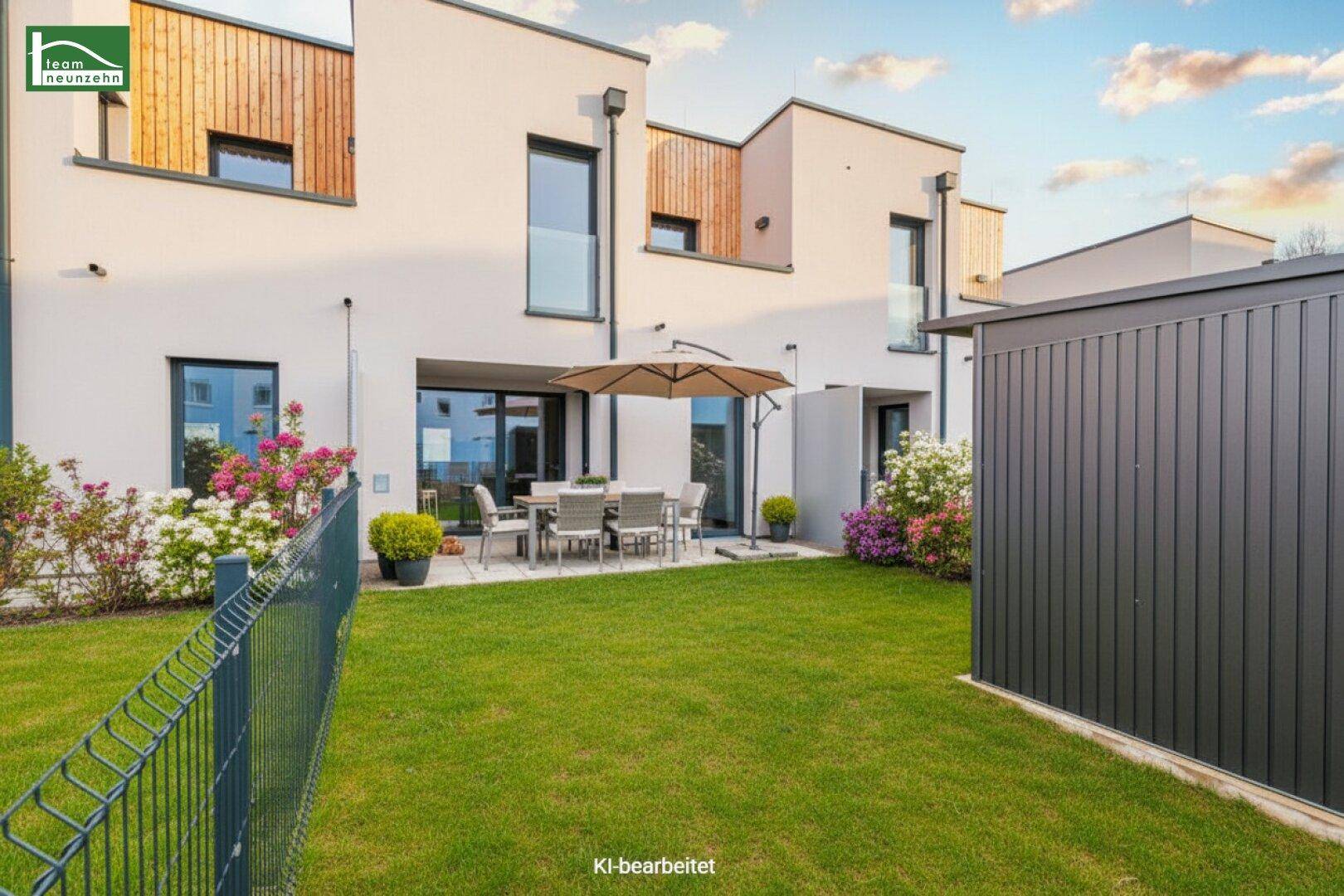 Gepflegter Gartenbereich mit Rasenfläche und möblierter Terrasse hinter einem modernen Neubau.