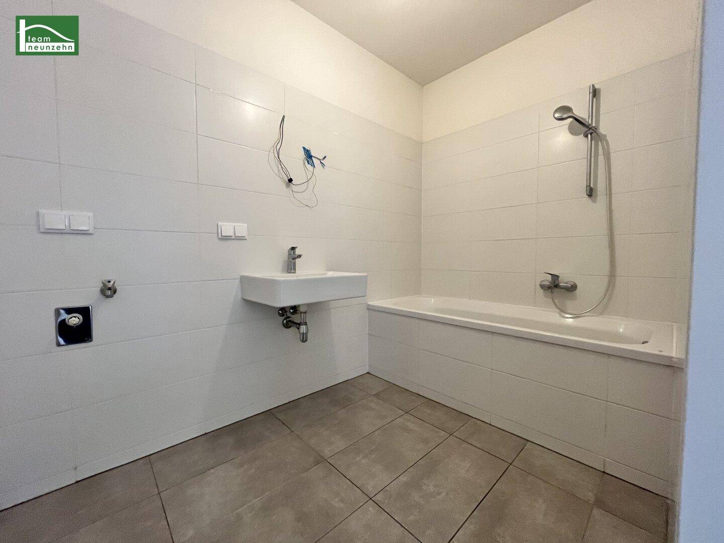 Helles Badezimmer mit Badewanne, modernem Waschbecken und weißen Fliesen.