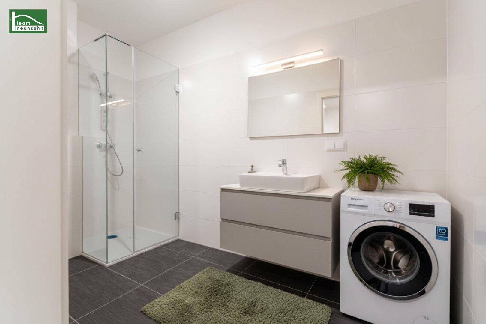 Modernes Badezimmer mit Glasdusche, Waschmaschine und dunklen Bodenfliesen.
