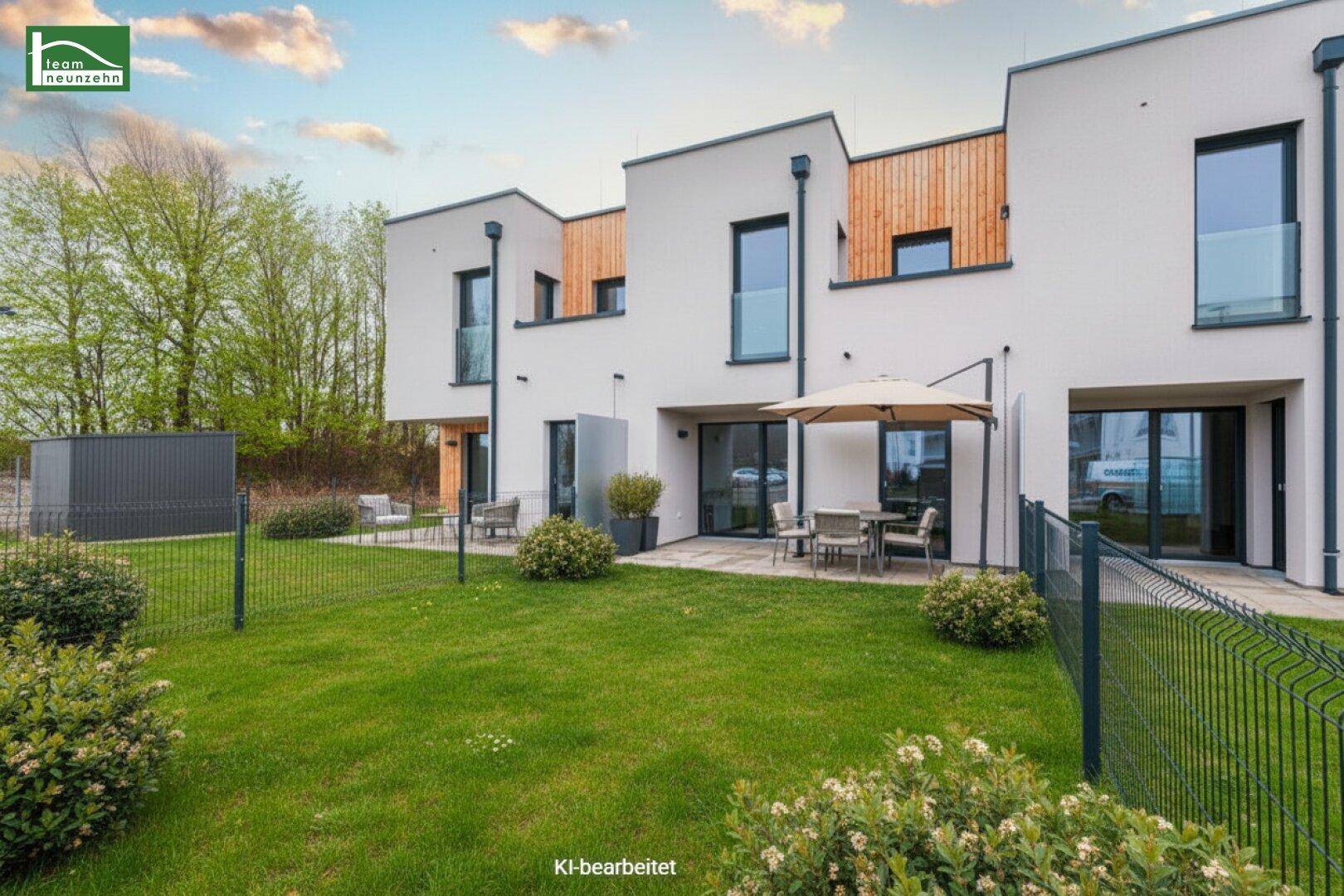 Moderne Reihenhäuser mit weißer Fassade, großen Fenstern und gepflegtem Garten mit Terrasse und Sitzbereich.