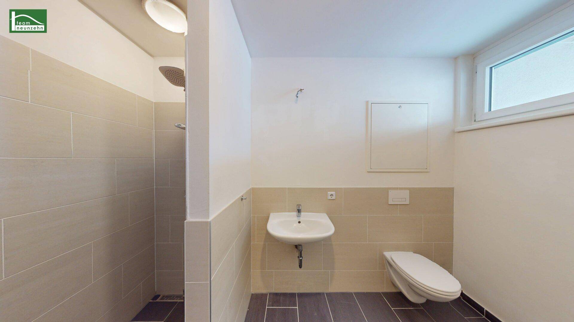 Modernes Badezimmer mit Dusche, WC und Fenster für natürliche Belüftung.