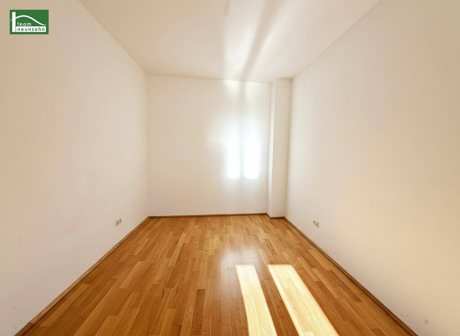 Ruhiges Zimmer mit Parkettboden und einem Fenster, das natürliches Licht spendet.