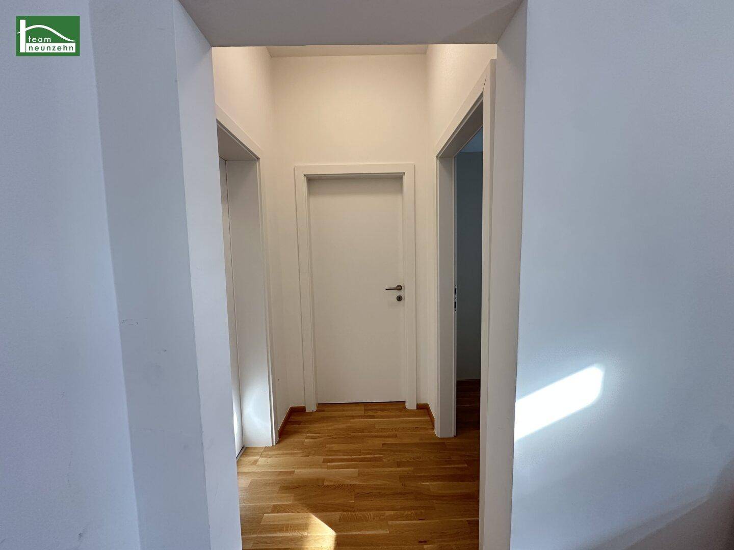 Heller Flur mit Holzboden und mehreren Türen, die zu den angrenzenden Räumen führen.