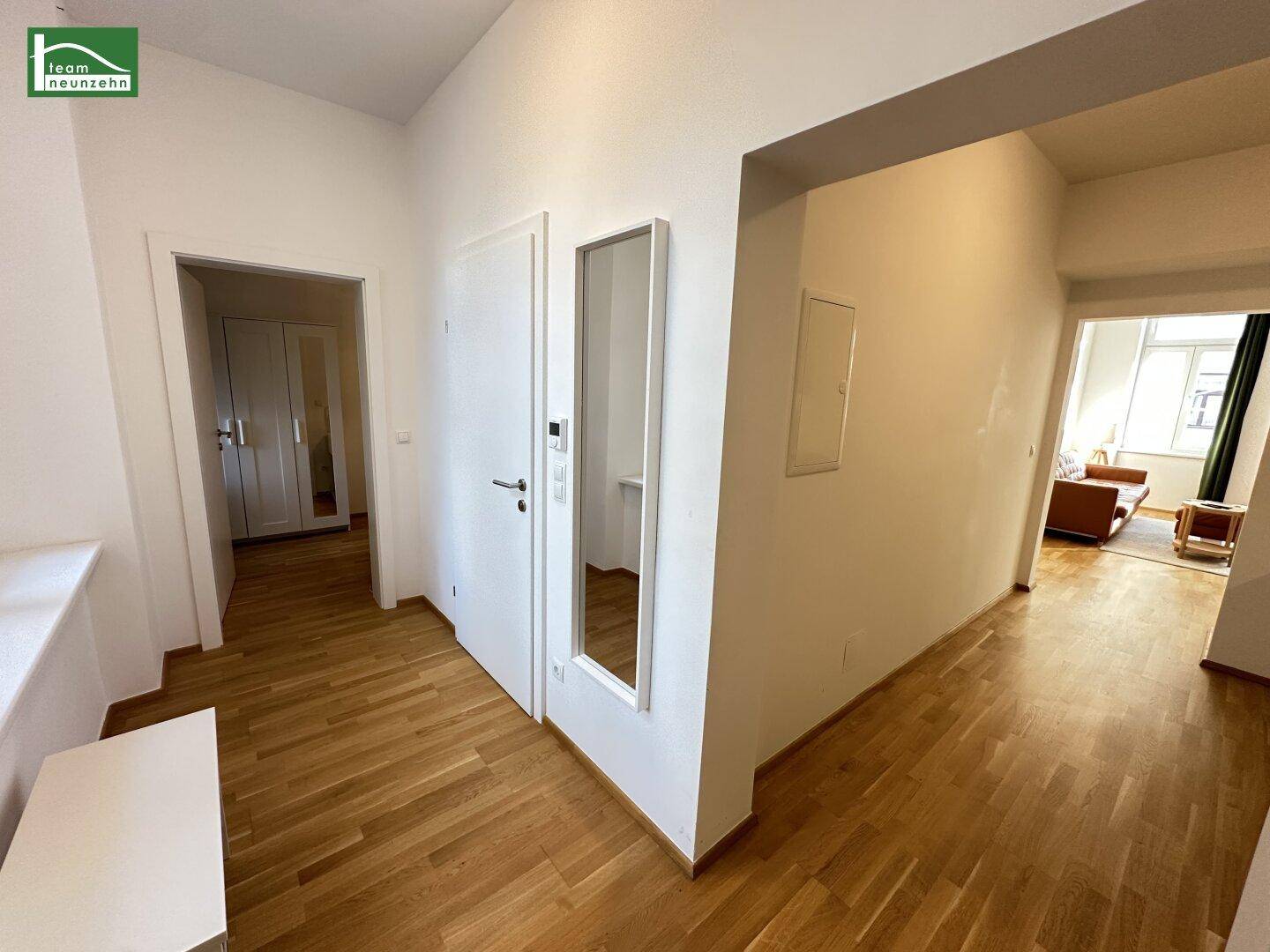 Eingangsbereich mit Holzboden, Spiegel und Zugang zu den Wohnbereichen.