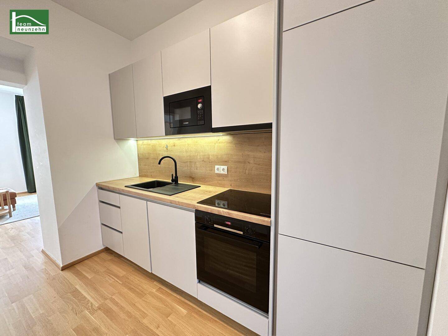 Detailansicht der modernen Küche mit Induktionskochfeld, Backofen und Mikrowelle.