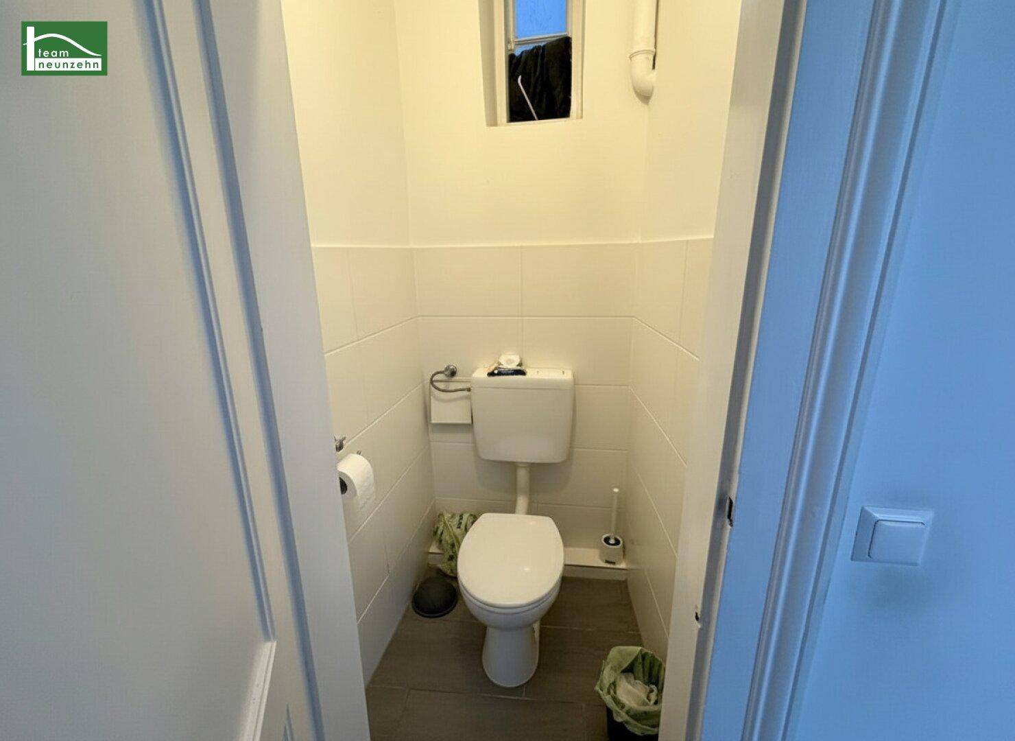Kleines Gäste-WC mit Toilette und einem kleinen Fenster für Belüftung und Tageslicht.