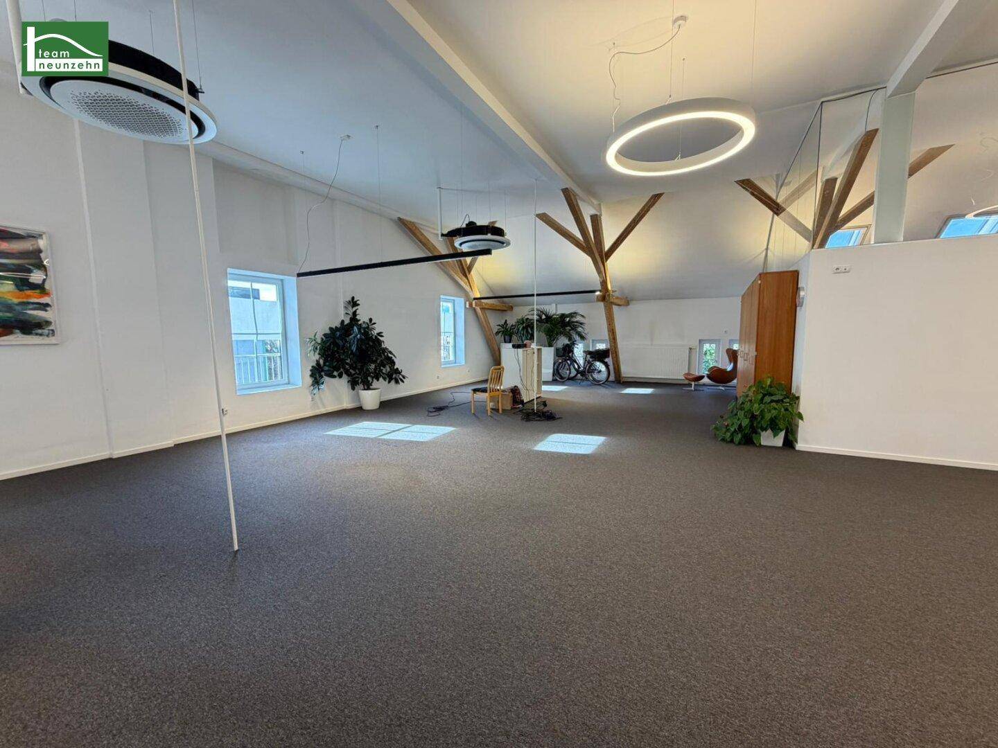 Heller und geräumiger Bürobereich mit Teppichboden, hohen Decken und modernen Ringlampen, ideal für flexible Arbeitsplätze.