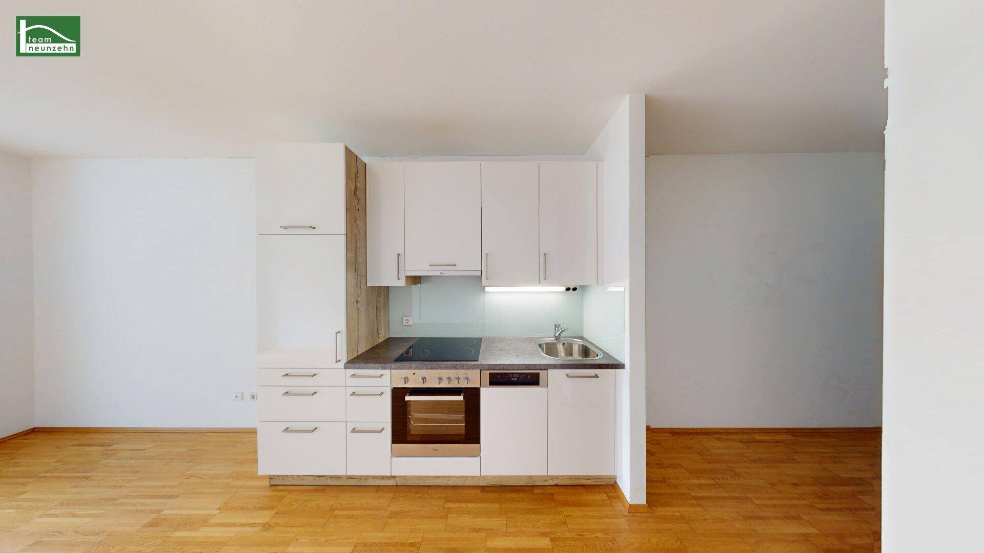Moderne Küchenzeile mit weißen Schränken, integriertem Backofen und Kochfeld.