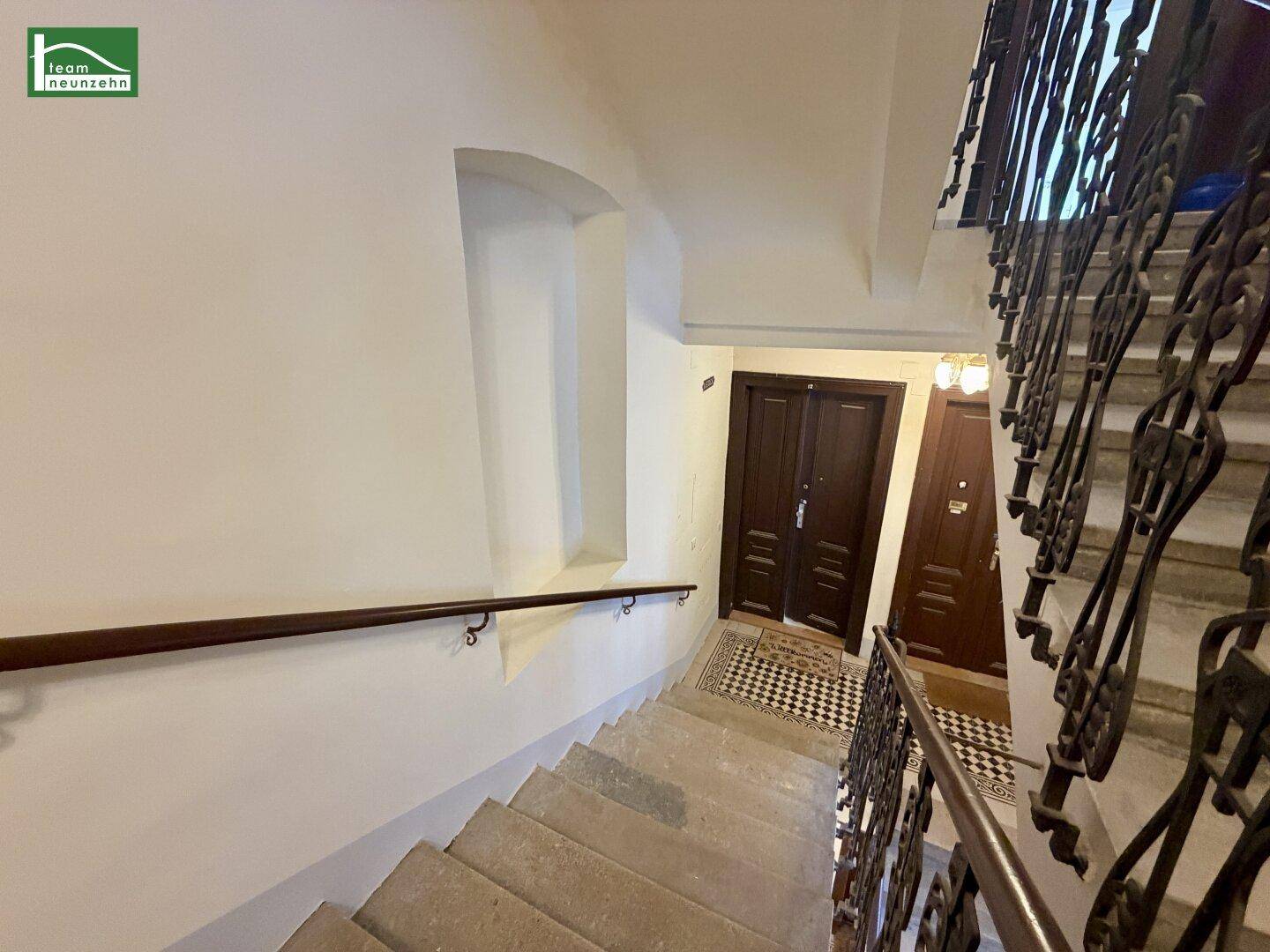 Historisches Treppenhaus mit Steinstufen, schmiedeeisernem Geländer und Handlauf in einem Altbau.