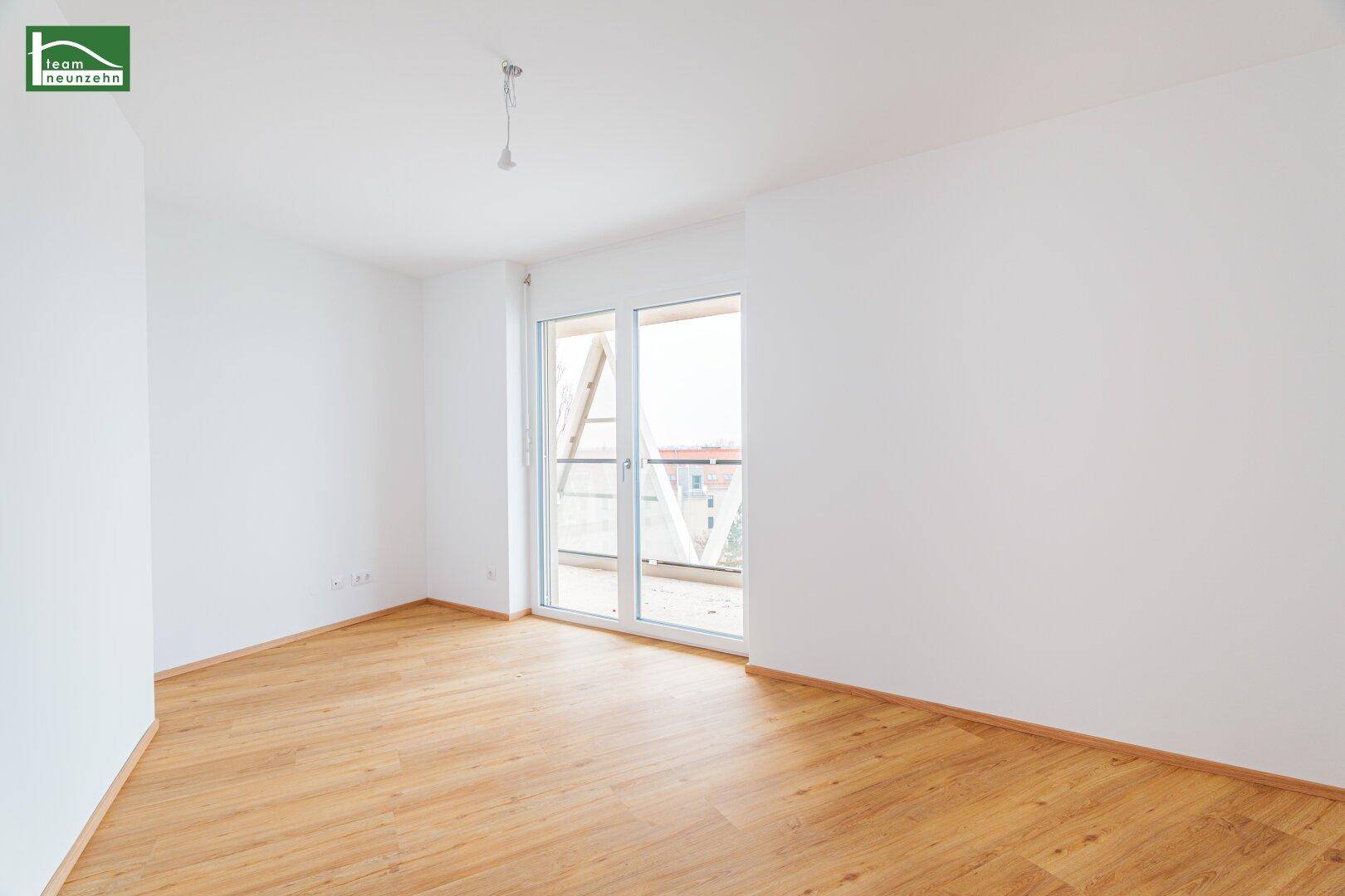 Helles Zimmer mit Holzboden und Balkonzugang, ideal als Schlaf- oder Arbeitszimmer.