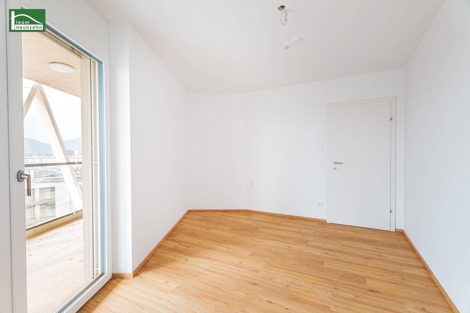 Unmöbliertes Zimmer mit Balkonzugang und hellem Holzfußboden, vielseitig nutzbar.