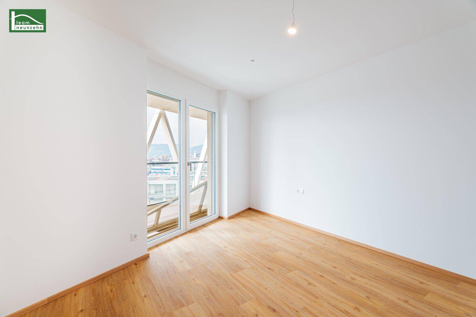 Helles Zimmer mit Holzboden und Zugang zu einem Balkon, ideal für ein Schlafzimmer.