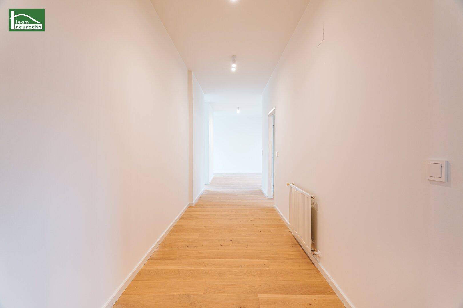 Langer, heller Flur mit Parkettboden, der die verschiedenen Bereiche der Wohnung verbindet.