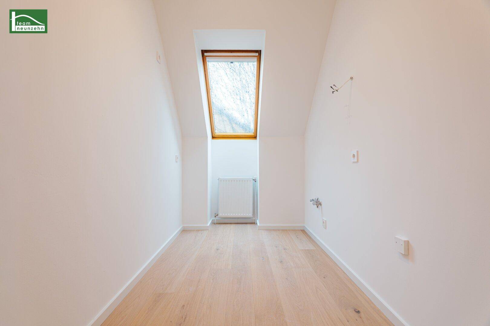 Kleines Zimmer im Dachgeschoss mit einem Dachfenster und hellem Parkettboden.