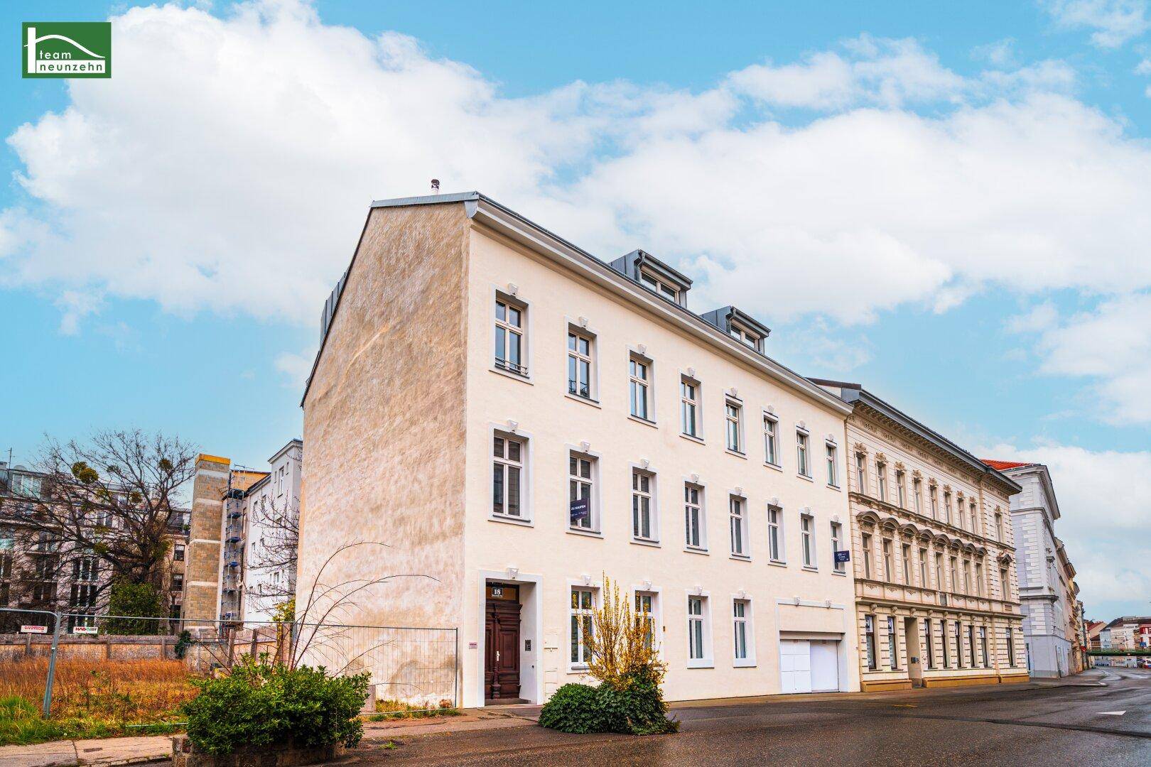 Klassisches Mehrfamilienhaus mit heller Fassade und großen Fenstern an einer Stadtstraße.