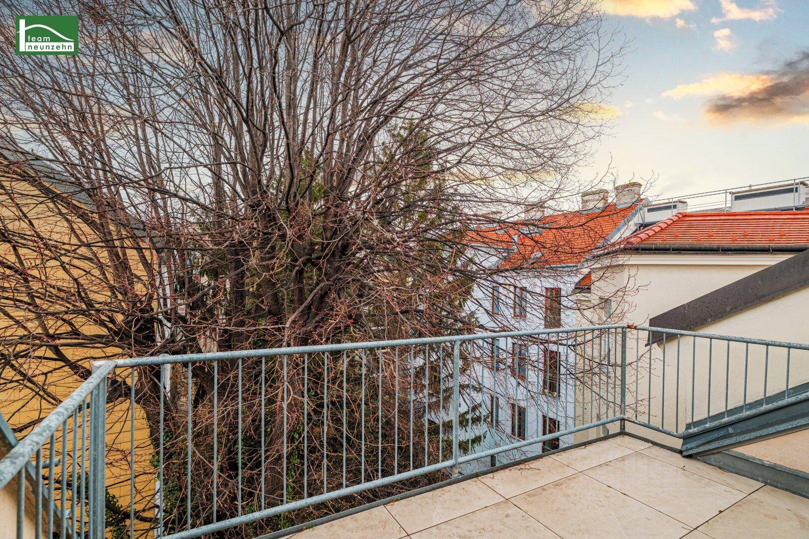 Geräumiger Balkon mit Fliesenboden und Blick auf die umliegenden Bäume und Dächer.