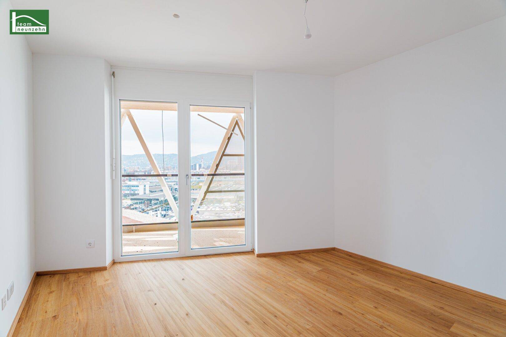 Helles Schlafzimmer mit Laminatboden und Zugang zum Balkon mit Panoramablick.