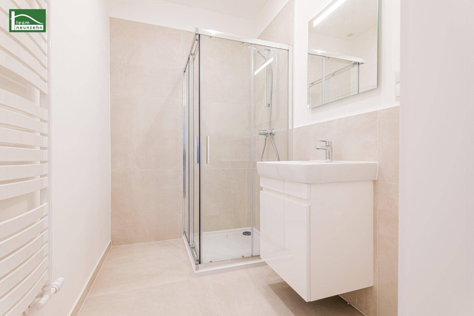 Modernes Badezimmer mit Duschkabine, Waschbecken und beheiztem Handtuchhalter.