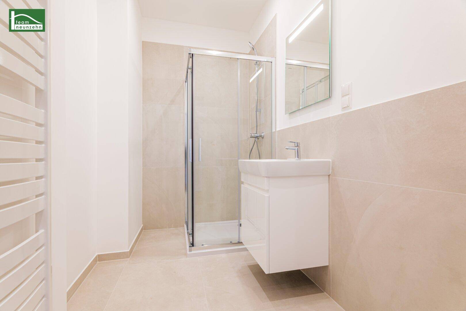 Modernes Badezimmer mit Duschkabine, Waschbecken und beheiztem Handtuchhalter.