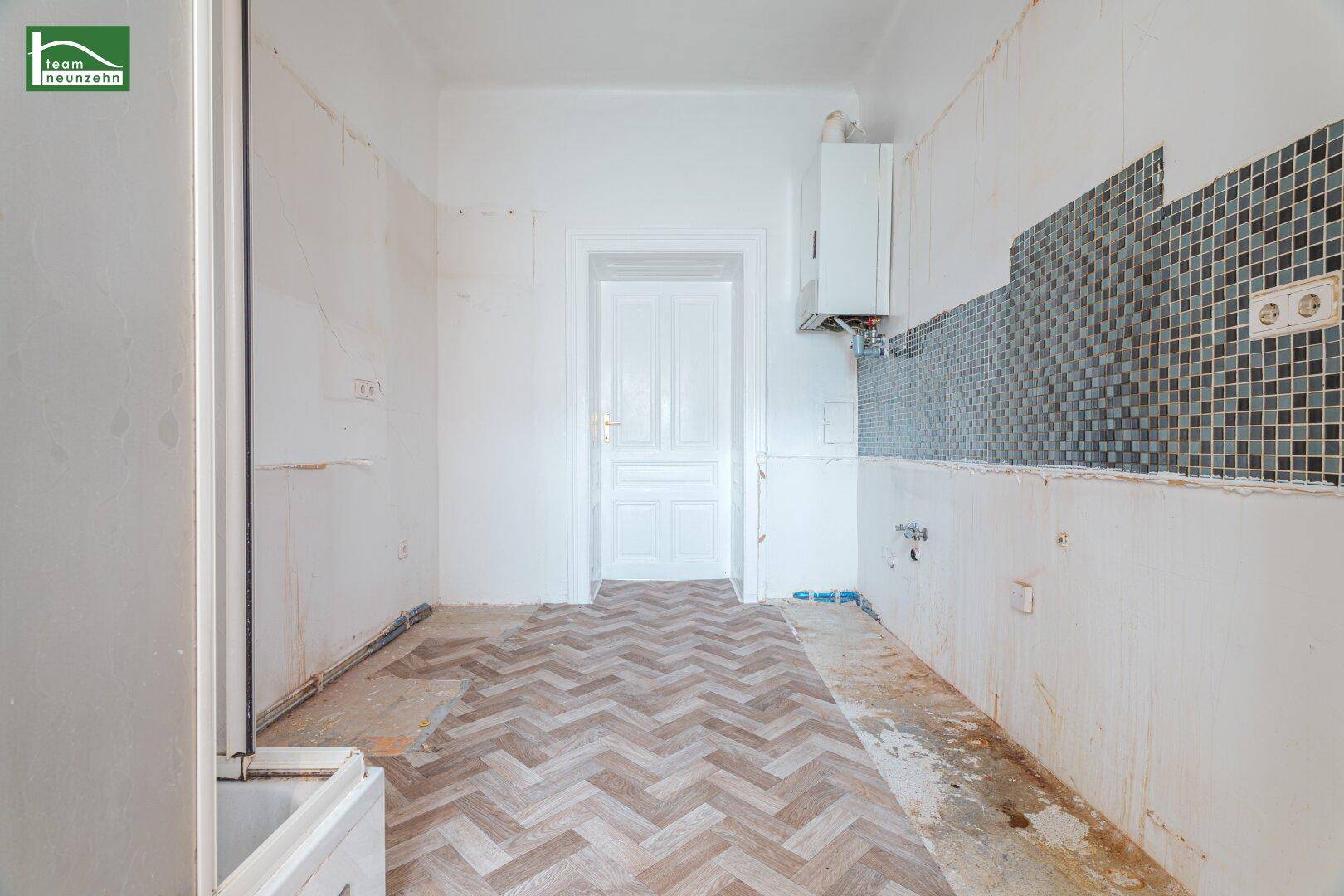 Unfertige Küche mit Fliesen an der Wand und sichtbaren Installationen, bereit für den Ausbau.
