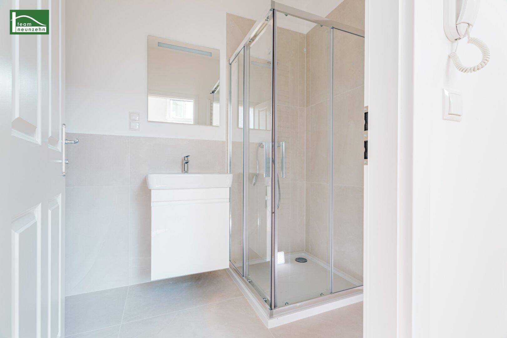 Modernes Badezimmer mit Duschkabine, Waschbecken und hellen Fliesen, in neuwertigem Zustand.
