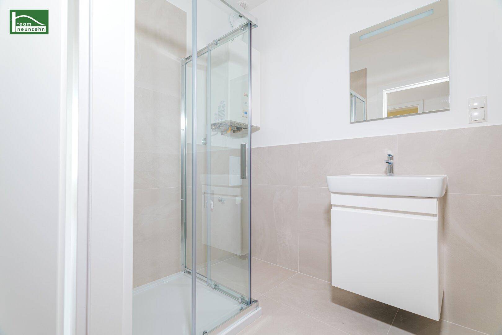 Modernes Badezimmer mit Duschkabine, Waschbecken und großem Spiegel.