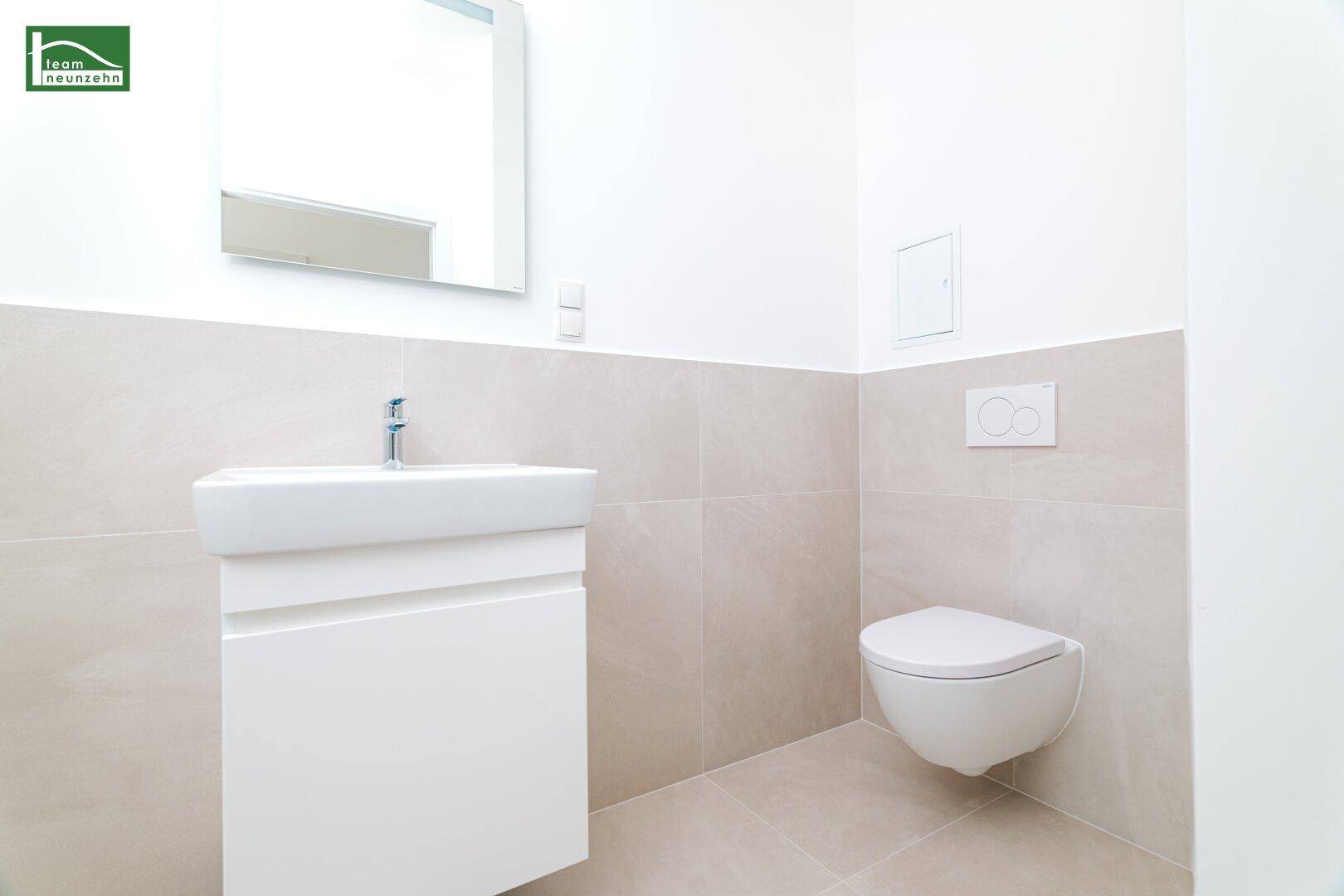 Helles Badezimmer mit wandhängendem WC, modernem Waschbecken und Fliesenboden.