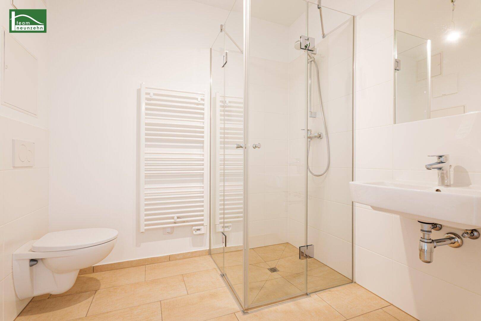 Modernes Badezimmer mit begehbarer Dusche, wandhängendem WC und beheiztem Handtuchhalter.
