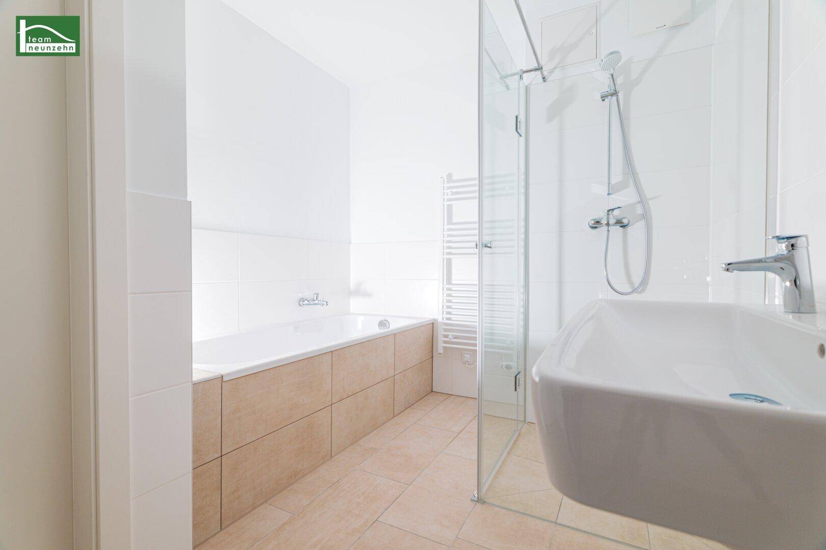 Helles Badezimmer mit Badewanne, Dusche und modernem Waschbecken.