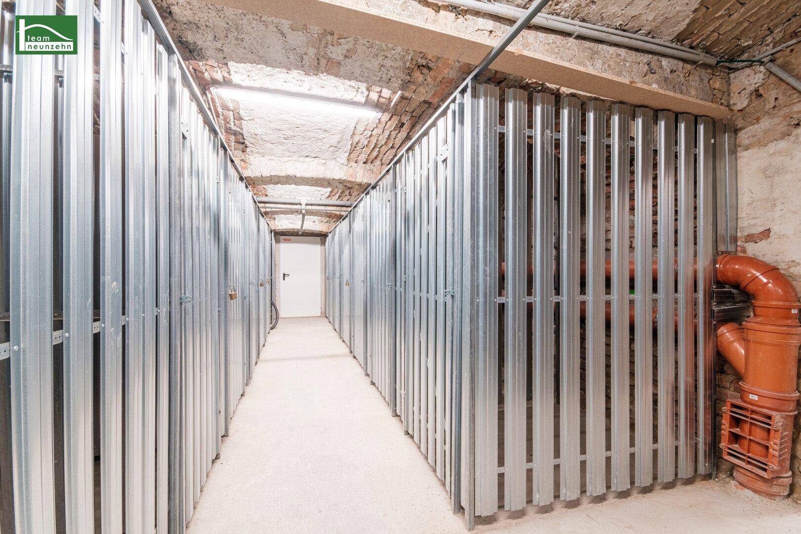 Funktionaler Kellerraum mit individuellen Abteilen aus Metall und sichtbaren Versorgungsleitungen.