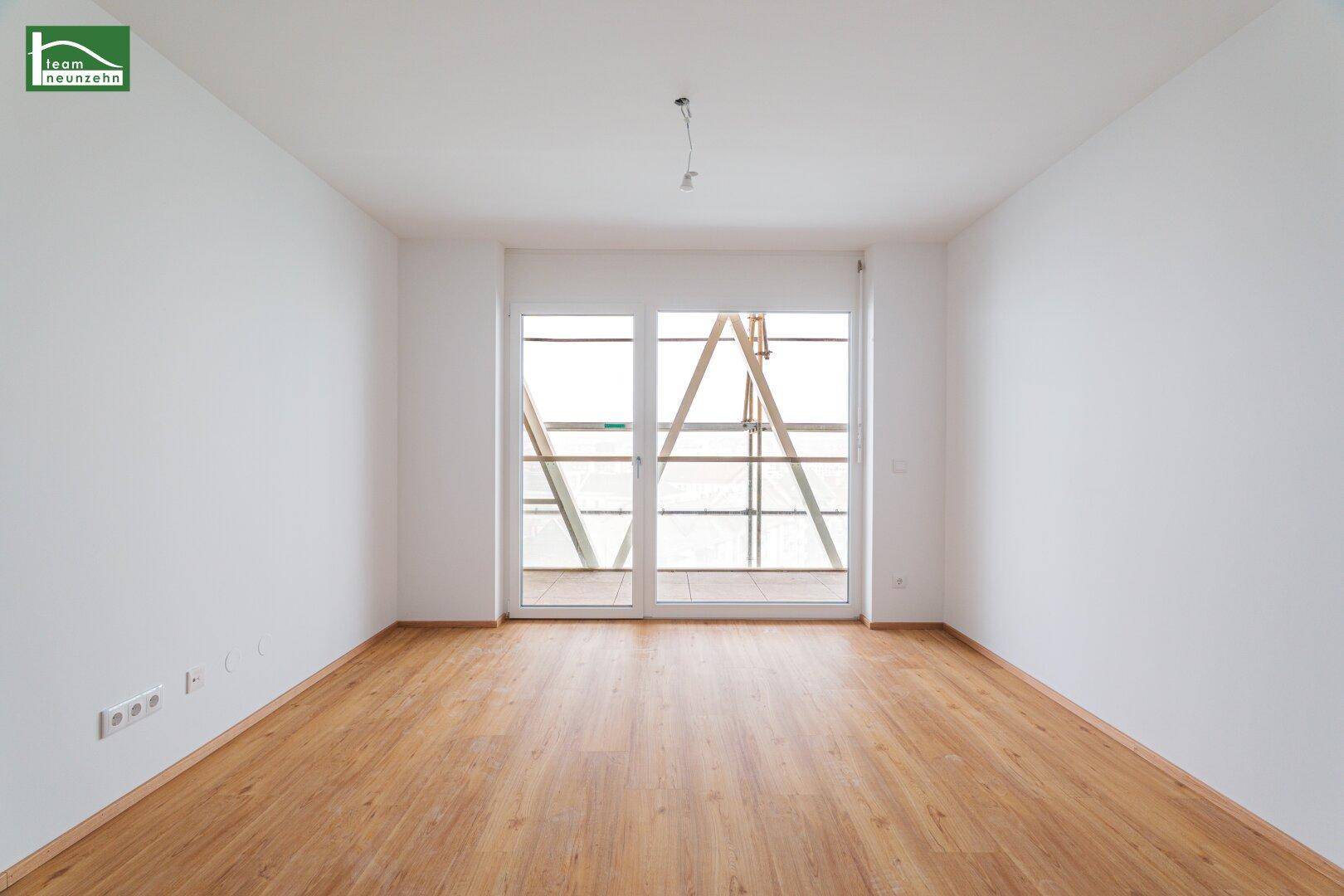 Leerer Raum mit hellem Laminatboden und Zugang zu einem Balkon.