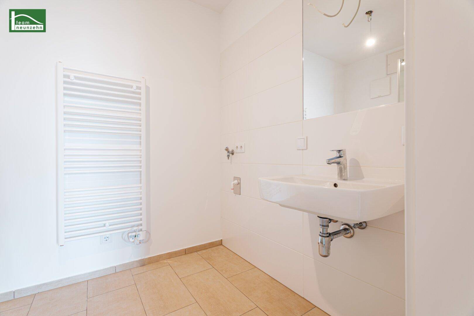 Modernes Badezimmer mit Waschbecken, Spiegel und beheiztem Handtuchhalter an der Wand.