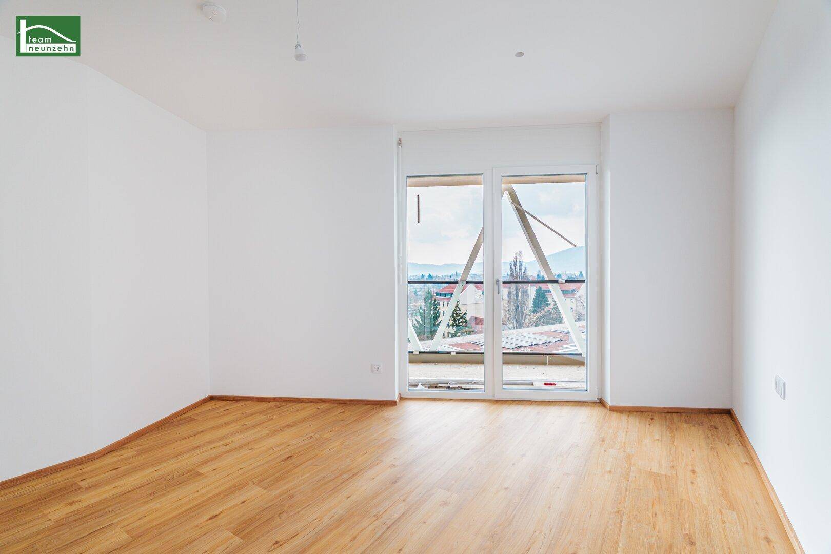 Geräumiges Zimmer mit Laminatboden und großen Fenstern, ideal als Schlaf- oder Arbeitszimmer.