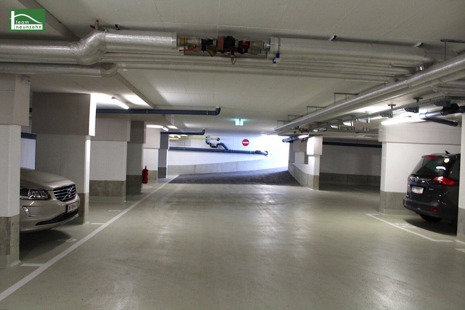 Helle Tiefgarage mit mehreren Stellplätzen und Zufahrtsrampe.