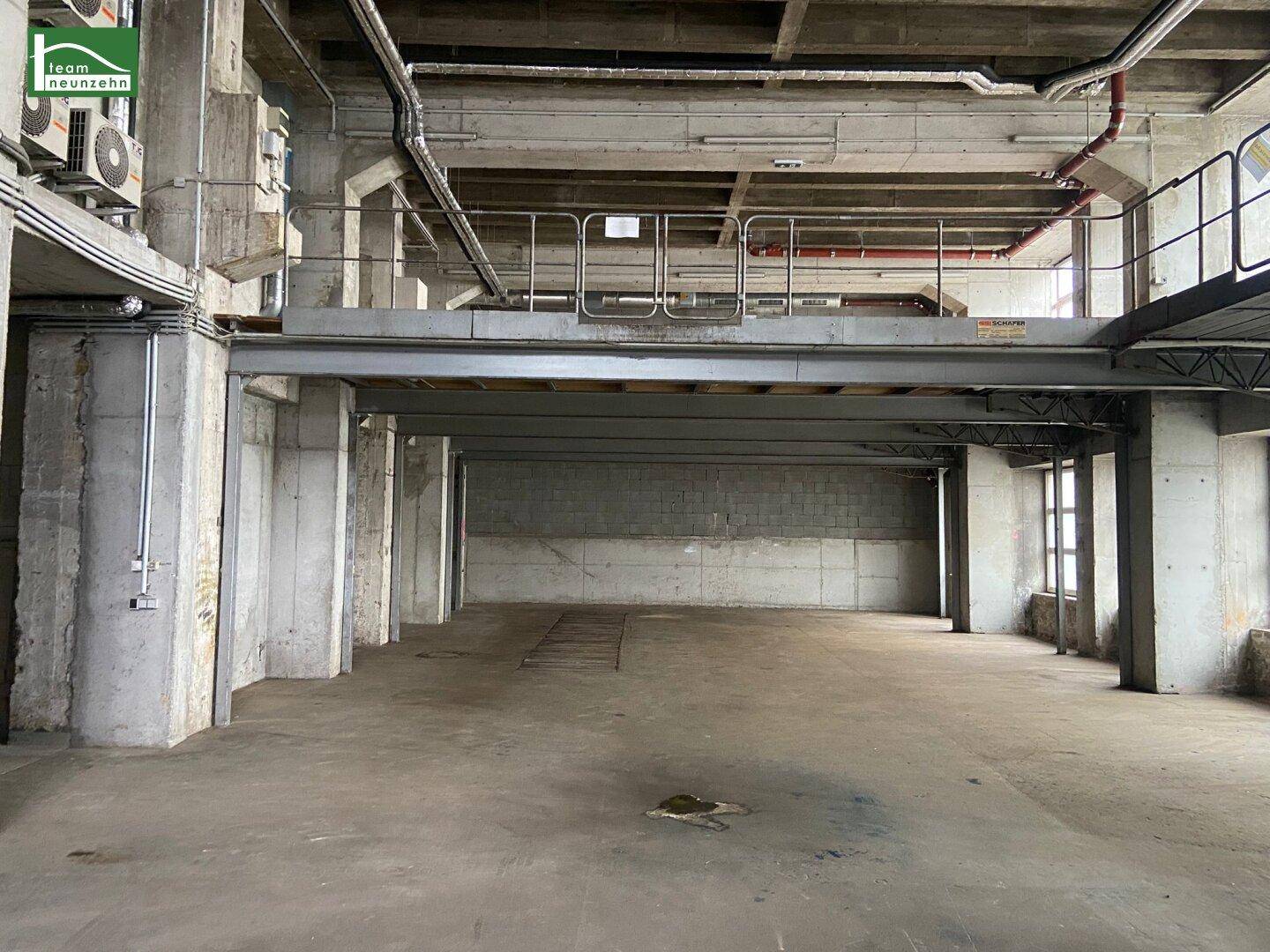 Weitläufiger Industrieraum mit hohen Decken, Betonwänden und sichtbaren Installationen und Stahlträgern.
