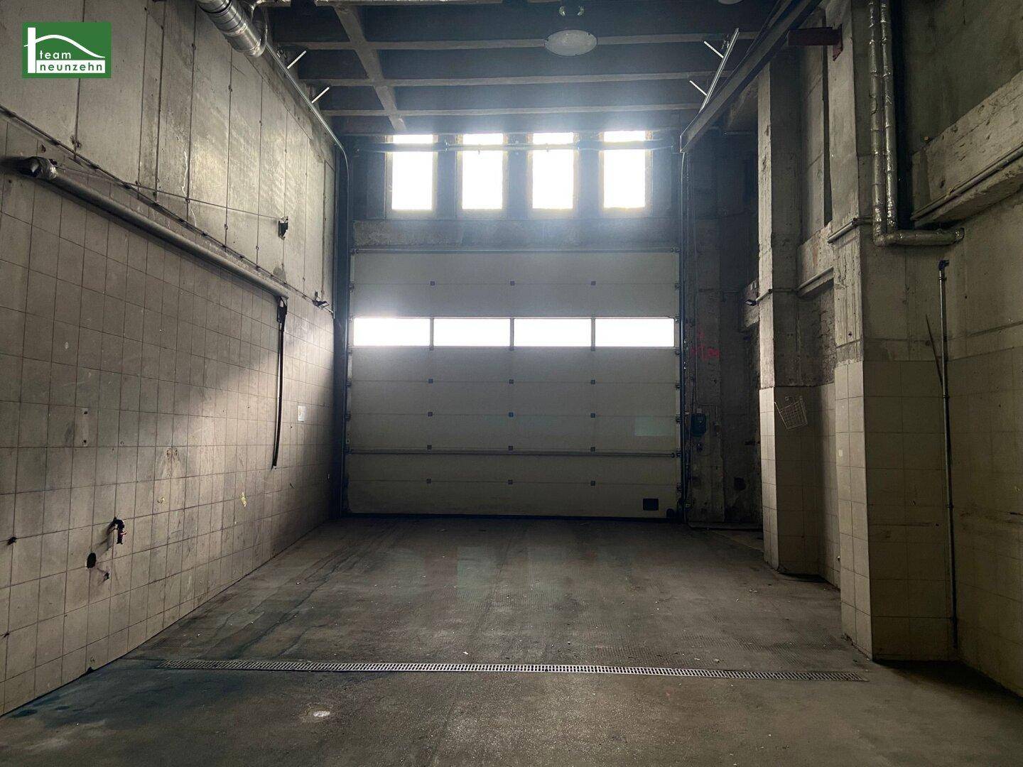 Große Rolltor-Einfahrt in einem Lagerbereich mit Fliesenwänden und Betonboden.