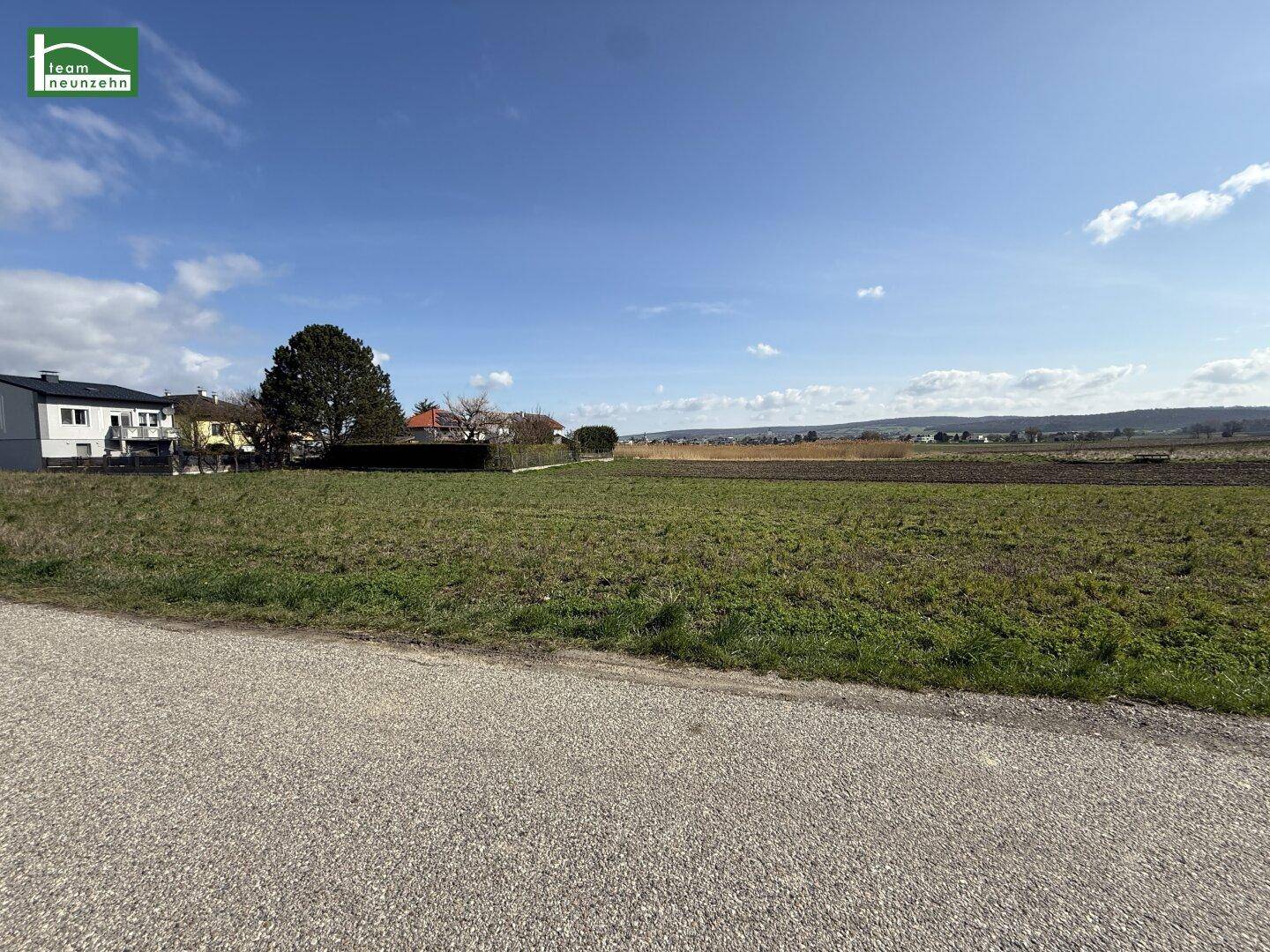 Weitläufiges Feld mit Blick auf die ländliche Umgebung und angrenzende Wohnhäuser.