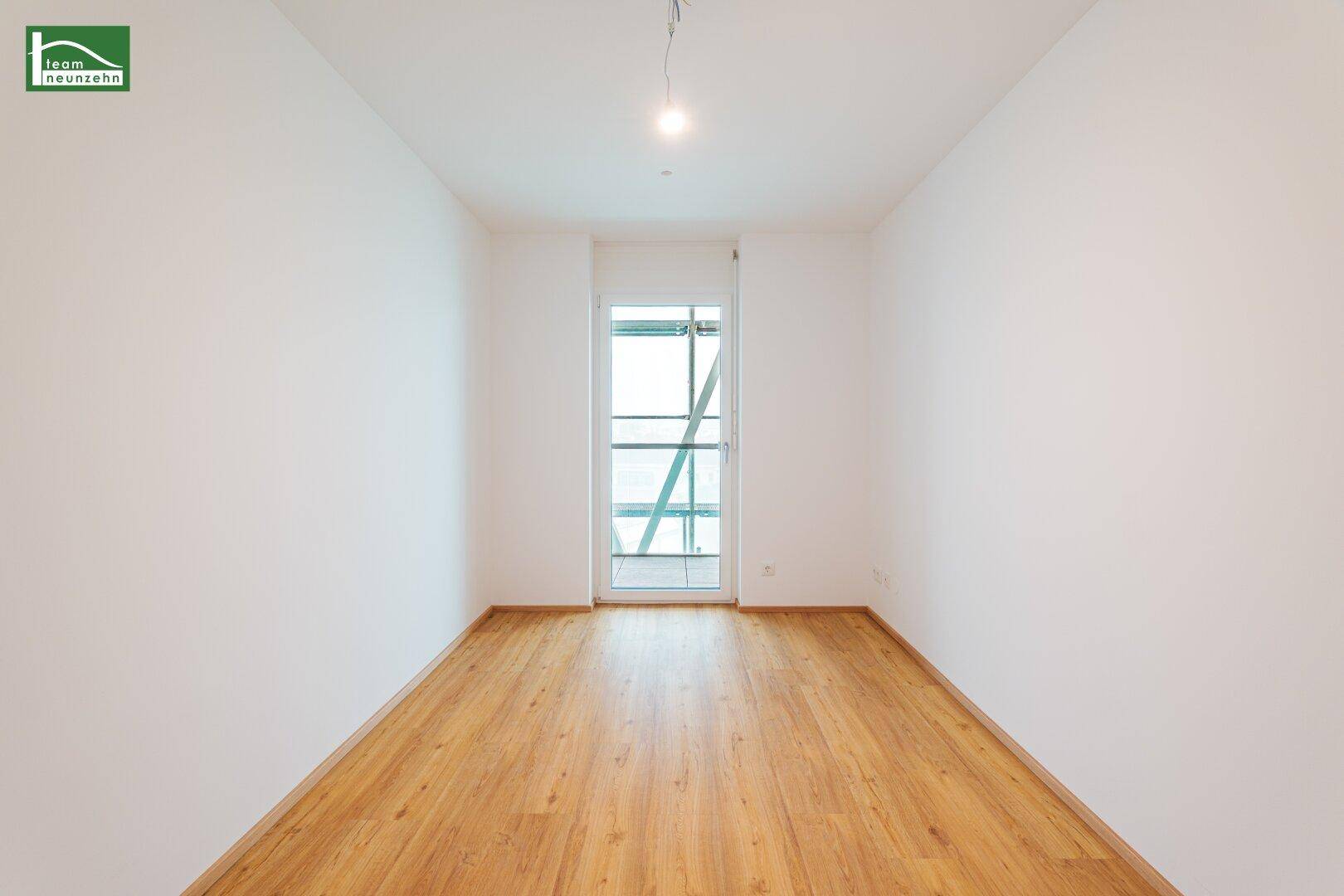 Heller Raum mit Holzfußboden und Balkontür, ideal als Schlafzimmer nutzbar.