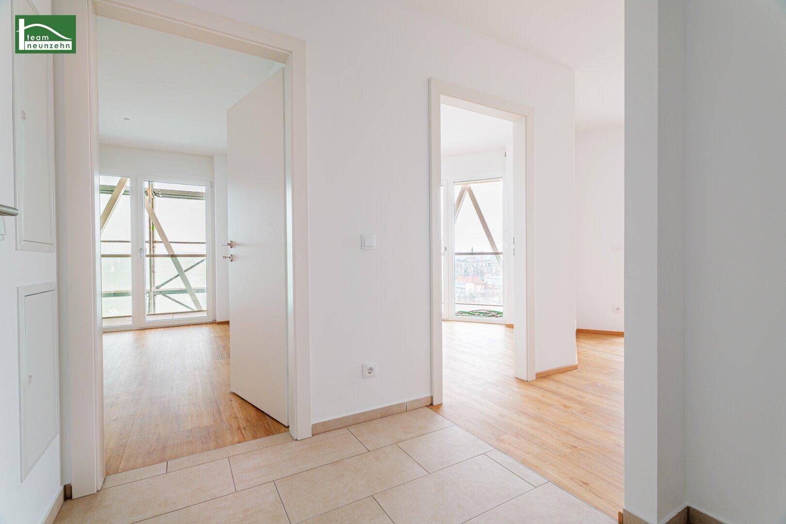 Heller Flur mit Fliesenboden, der zu weiteren Räumen mit Holzboden führt.
