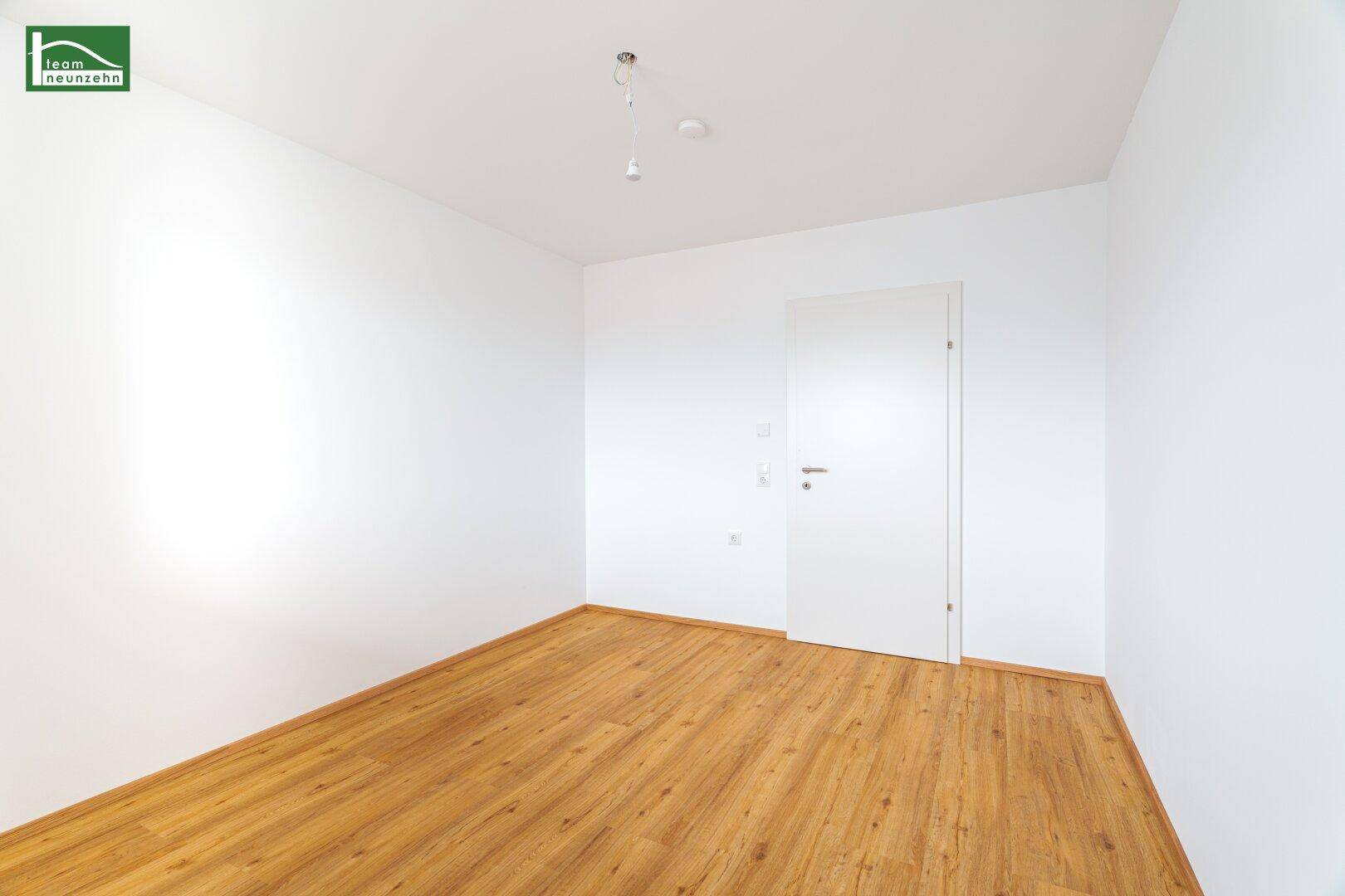 Leeres Zimmer mit Parkettboden und weiß gestrichenen Wänden, bereit zur individuellen Gestaltung.