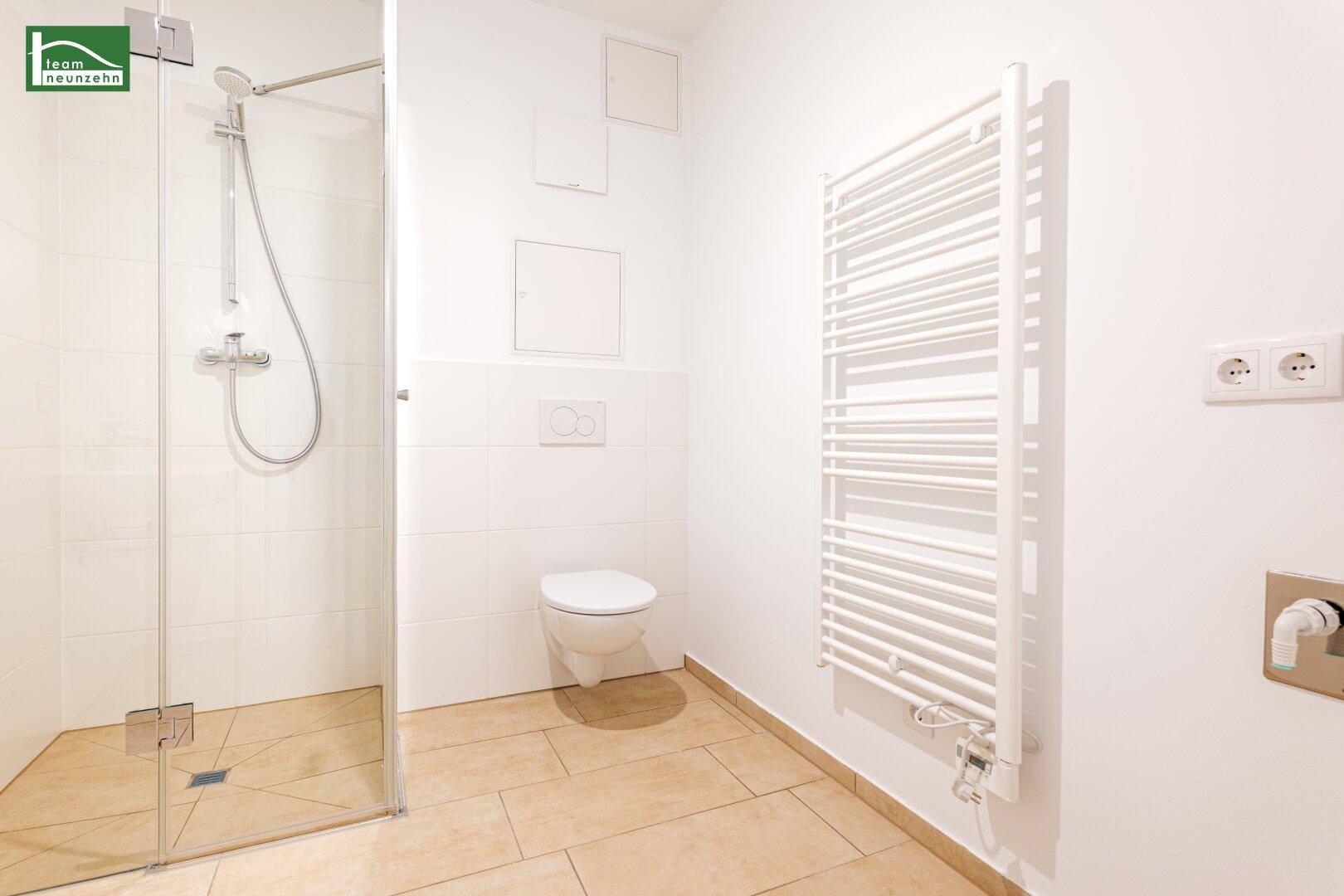 Helles Badezimmer mit Dusche, wandhängendem WC und beheiztem Handtuchhalter.
