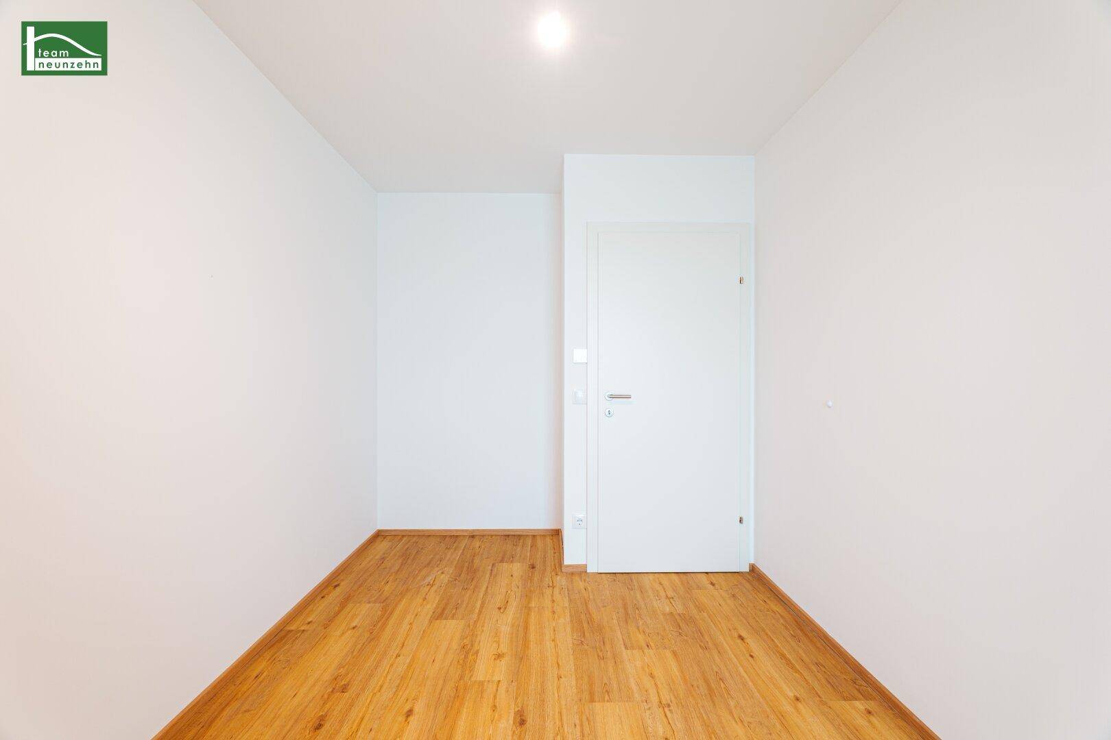 Leerer Raum mit Holzboden und weißer Tür, bereit für individuelle Gestaltung.