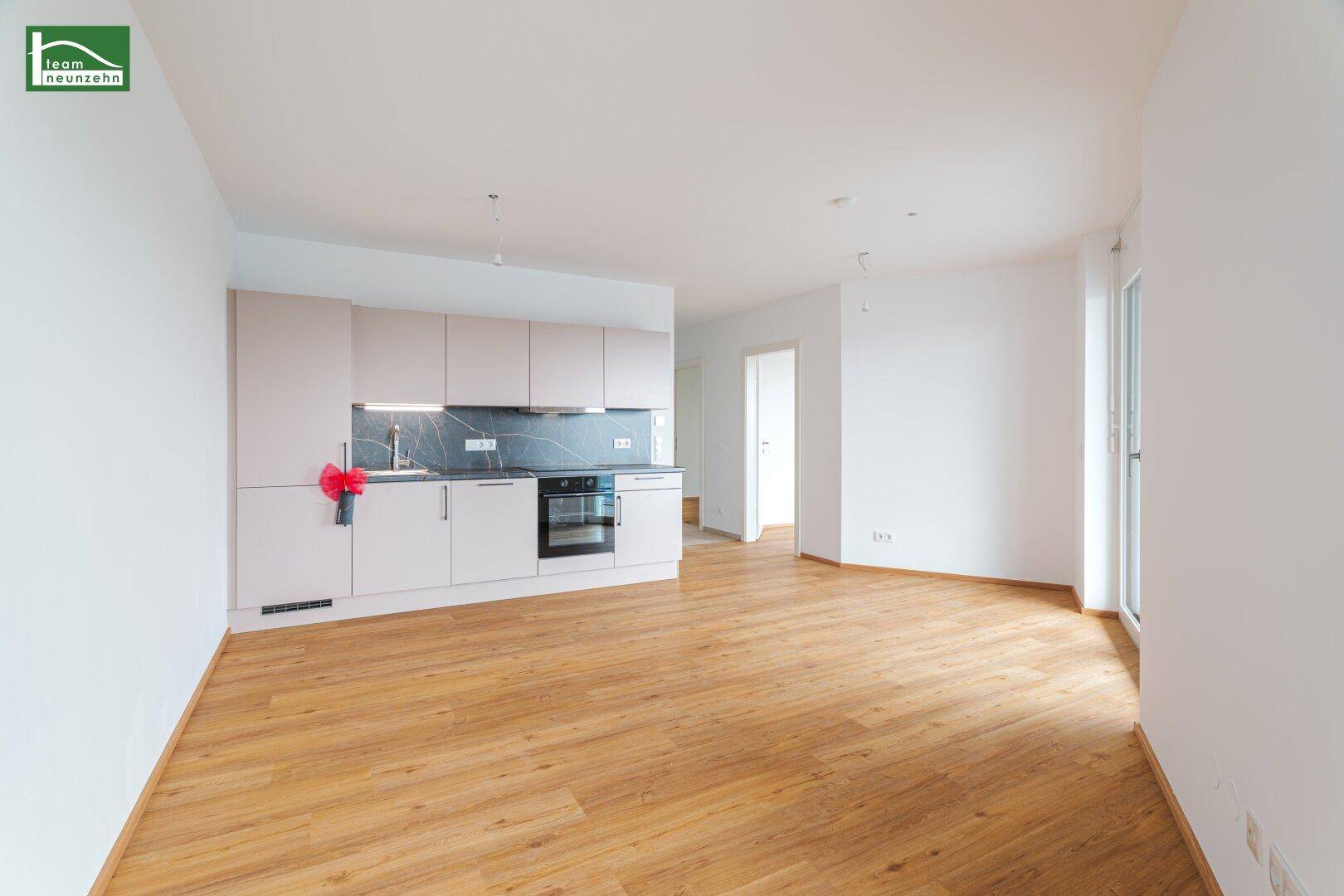 Moderne Einbauküche in hellem Farbton mit dunkler Arbeitsplatte in einem leeren Raum.