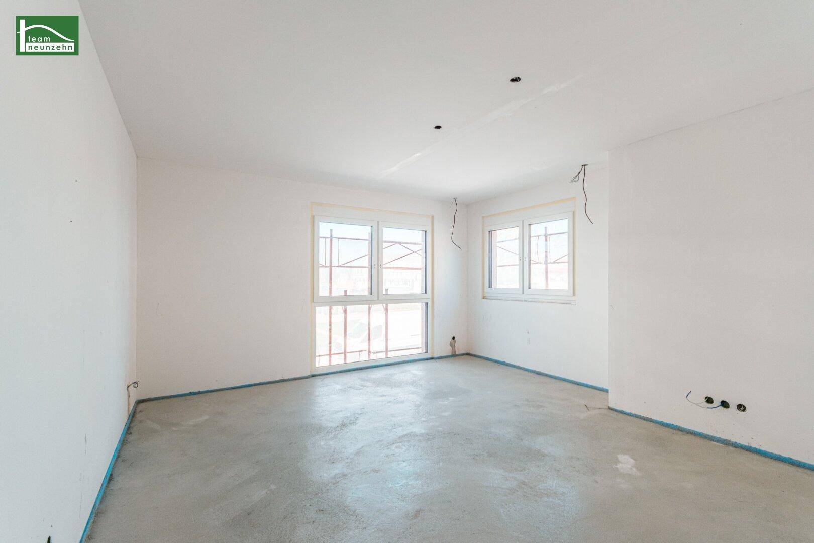 Unfertiges Zimmer mit zwei Fenstern und Betonboden, bereit für den weiteren Ausbau.