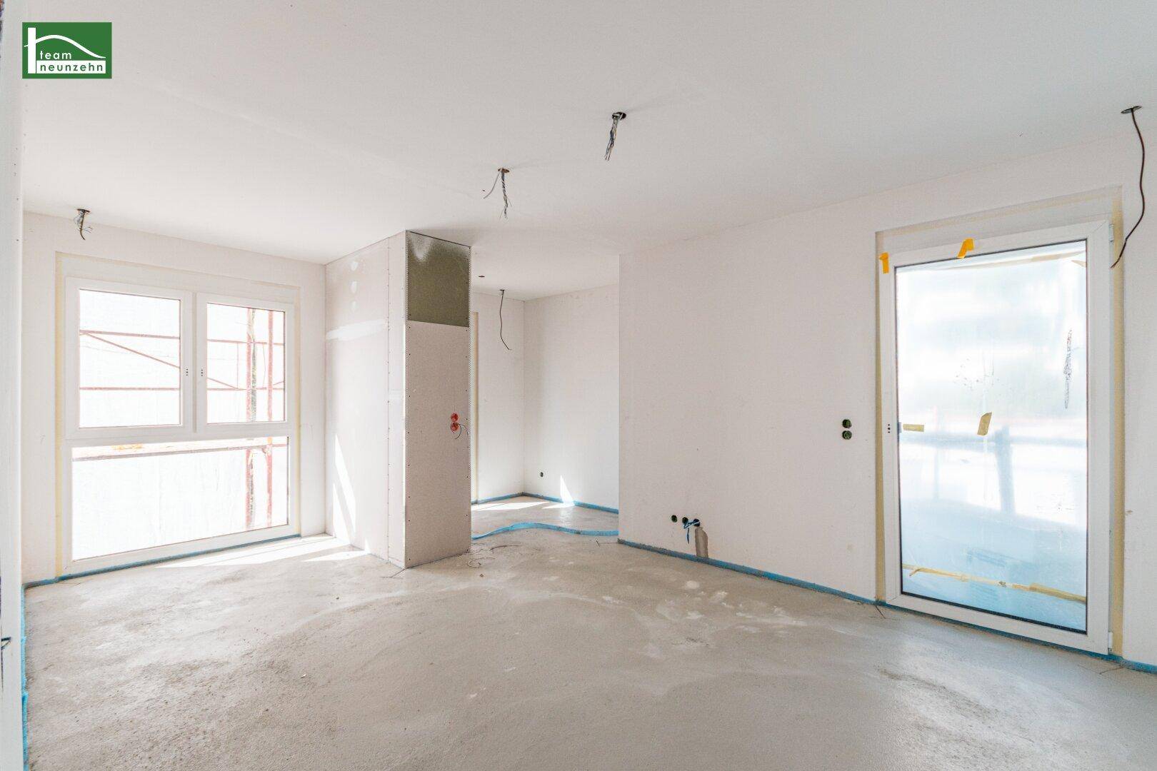 Unfertiger Innenraum mit Fenster und Tür zum Außenbereich, bereit für den weiteren Ausbau.