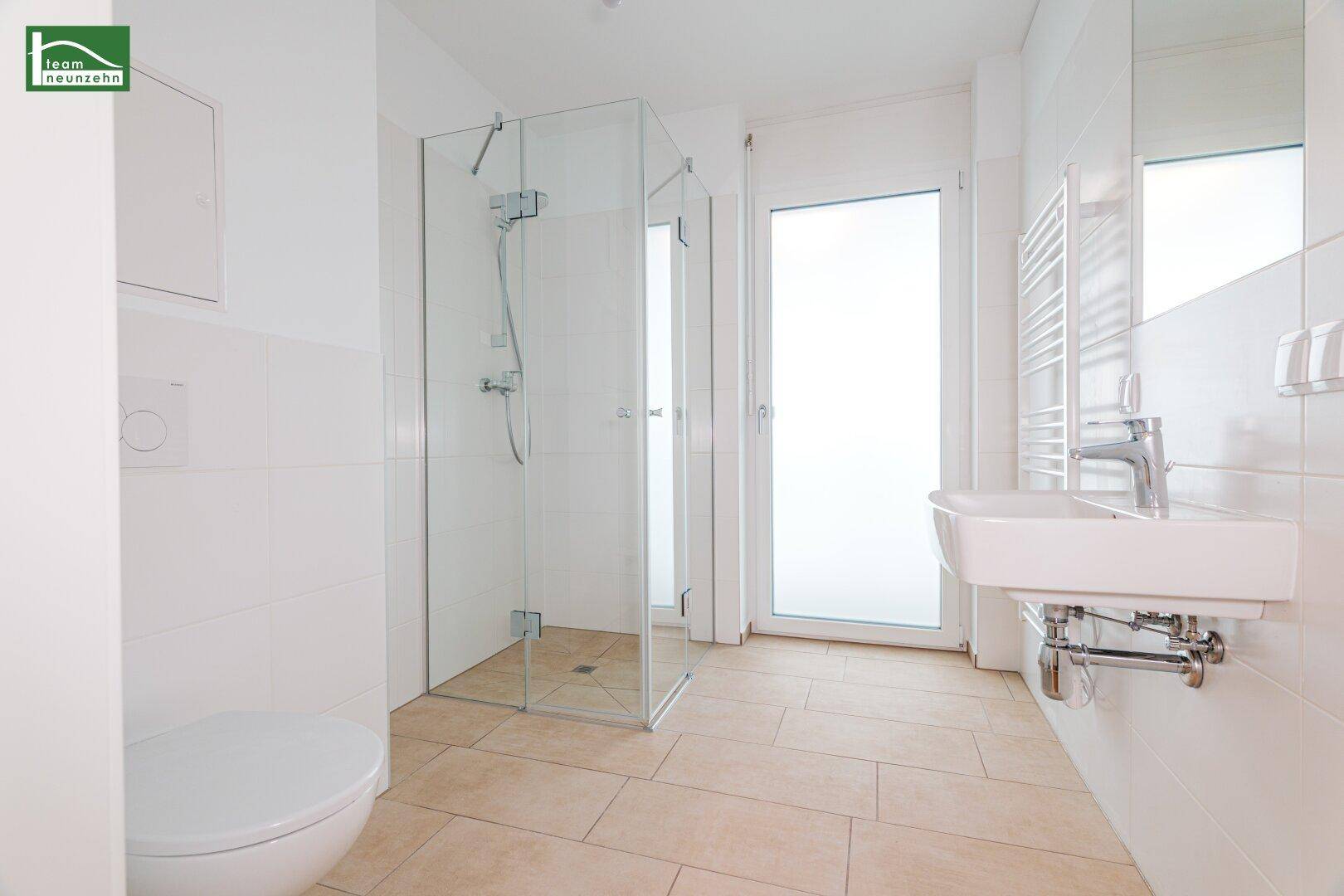 Modernes Badezimmer mit begehbarer Dusche, wandhängendem WC und hellem Fliesenboden.