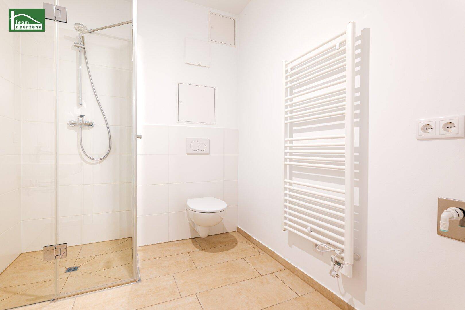 Modernes Badezimmer mit ebenerdiger Dusche, Wand-WC und beheiztem Handtuchhalter.