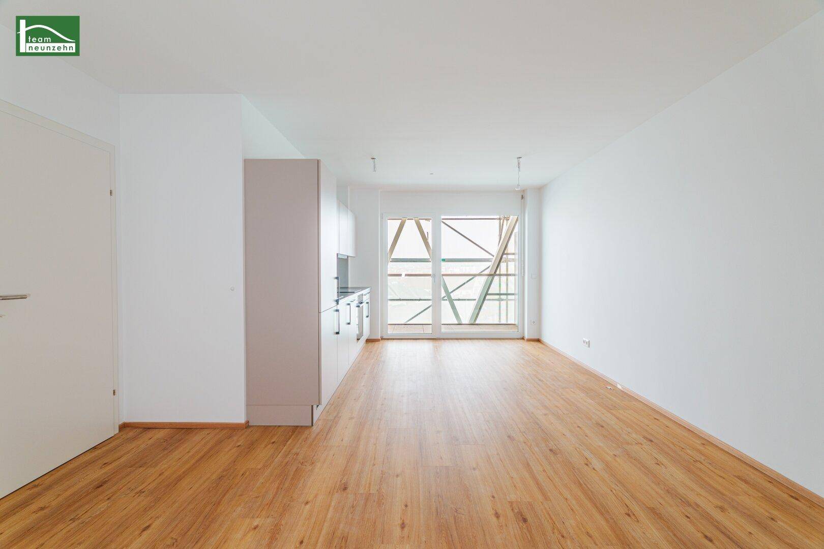 Geräumiger, heller Wohnbereich mit Küchenzeile und Zugang zu einem Balkon oder einer Terrasse.