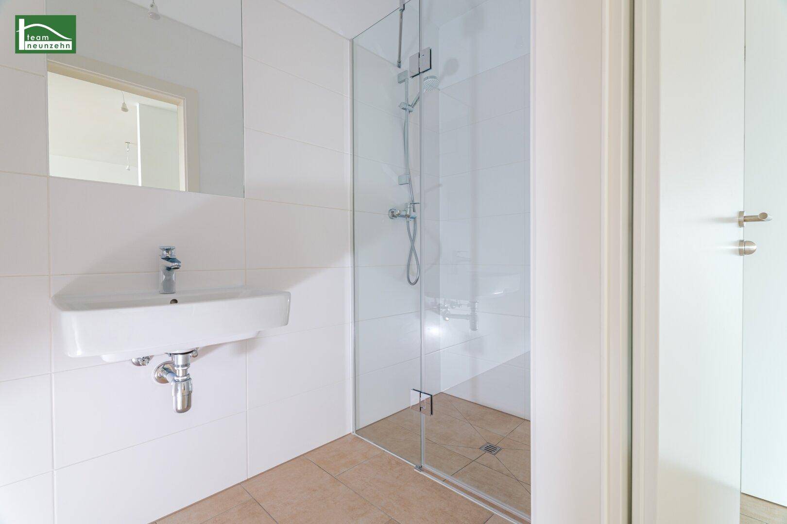 Modernes Badezimmer mit begehbarer Dusche, weiß gefliesten Wänden und Einzelwaschbecken.